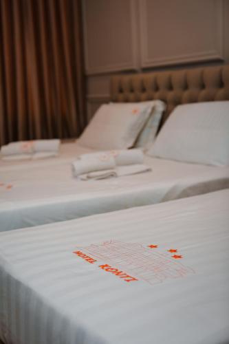 two beds in a hotel room with red writing on them at Hotel Konti in Korçë