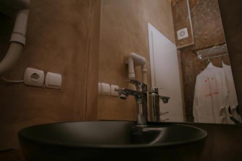 a bathroom with a sink with a faucet and a mirror at Hotel Konti in Korçë