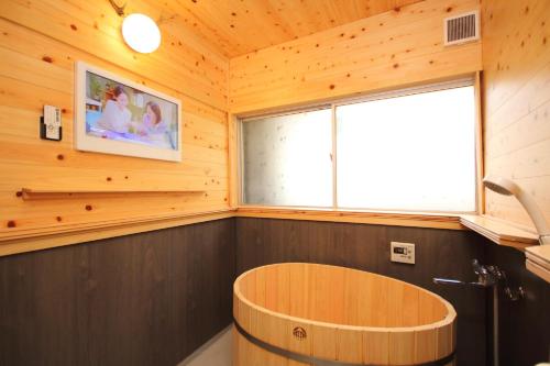 Cette chambre en bois dispose d'une grande fenêtre et d'une baignoire en bois. dans l'établissement Fuji Time Traveler, à Fujikawaguchiko