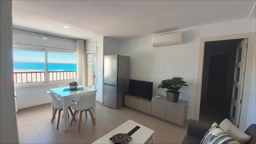 a living room with a table and a kitchen with a view of the ocean at Apartamentos Dins Mar Apto. 11 in Torredembarra