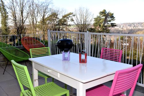 a white table with colorful chairs on a balcony at Le Refuge in Namur