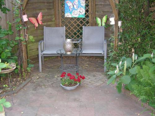 two chairs and a table in a garden with flowers at B&B overnachting de Margriet in Hardenberg