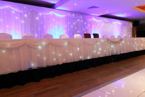 a stage with a long table with chairs and lights at Errigal Country House Hotel in Cootehill