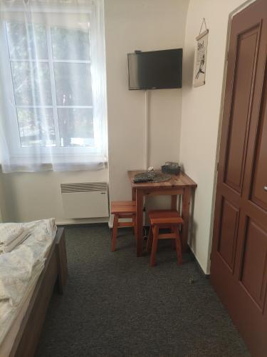a room with a bed and a table and a television at Penzion Klášterský mlýn in RejÅ¡tejn