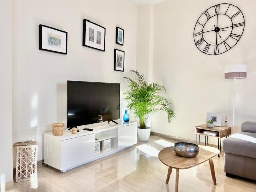 sala de estar con TV y reloj grande en la pared en Teodosio Apartment FREE PARKING & CENTRAL AC, en Sevilla