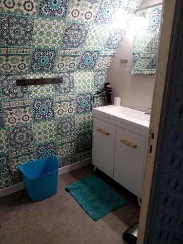 La salle de bains est pourvue d'un lavabo et d'un mur en carrelage. dans l'établissement À La Maison Du Bonheur, à Audruicq