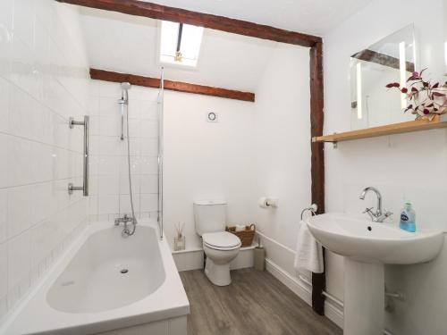 a bathroom with a tub and a toilet and a sink at Old Cart Shed in Lyneham