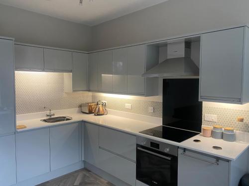 Una cocina con gabinetes blancos y un horno de estufa. en NiCheGetaway, en Shrewsbury