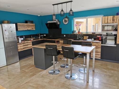 a kitchen with blue walls and a wooden table and chairs at Superbe Maison Jacuzzi+Piscine au cœur des vignes in Pfaffenheim