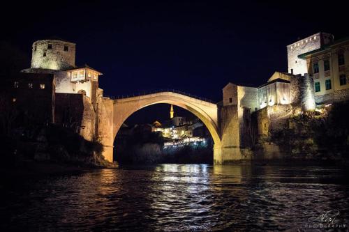 a bridge over a body of water at night at Studio Apartments KIM - Dilberovic in Mostar