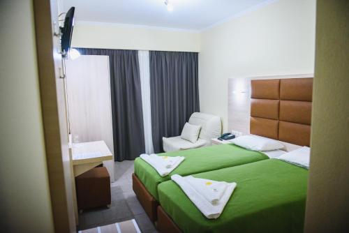 a hotel room with a green bed and a sink at Santa Rosa Hotel & Beach in Alexandroupoli