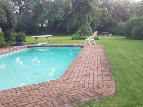 Victorian Villa Westdene Benoni في بينوني: مسبح مع كرسي وطاولة في ساحة
