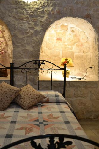 a bedroom with a bed with a lamp and a stone wall at Masseria Montanaro in Cisternino