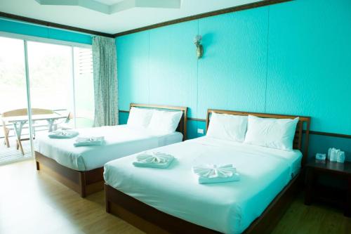 two beds in a room with blue walls at Suan Sai Yok Resort in Sai Yok