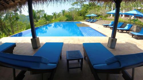 a swimming pool with blue chairs and umbrellas at Niyagama House in Galle