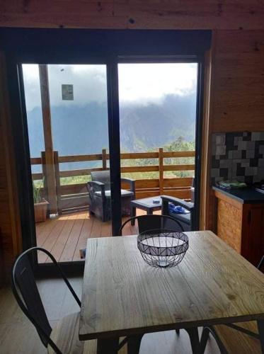 a table and chairs in a room with a balcony at Bungalow de la caz l'écho in Cilaos
