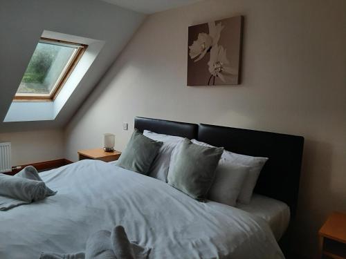 a bedroom with a bed with white sheets and a window at Holly Lodge in Alnwick