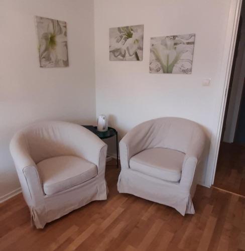 two white chairs in a living room with paintings on the wall at Breanäs Hotell in Immeln