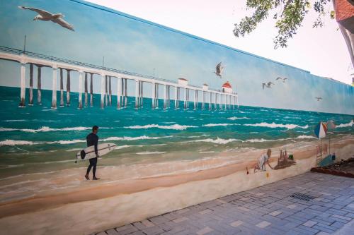 a mural of a man walking on the beach with a surfboard at Comfort Inn & Suites Huntington Beach in Huntington Beach