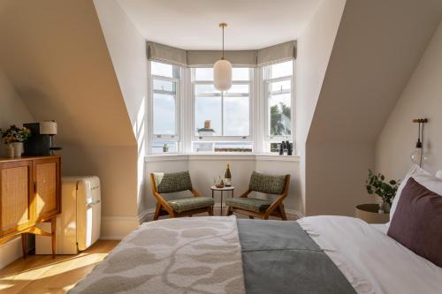 um quarto com uma cama, 2 cadeiras e uma janela em The Dundonald Guesthouse & Cottage em Culross