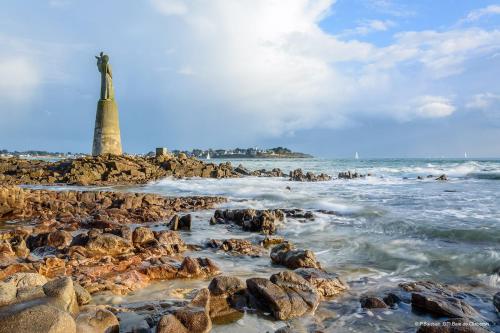 un phare sur la rive d'une plage rocheuse dans l'établissement Charmant studio les pieds dans l’eau à Locmariaquer, à Locmariaquer