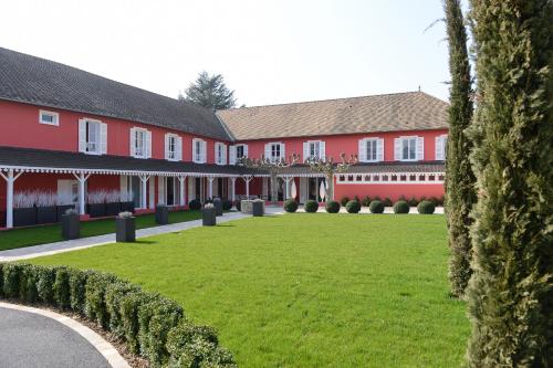 a row of red buildings with a green lawn at Les Maritonnes Parc & Vignoble in Romanèche-Thorins