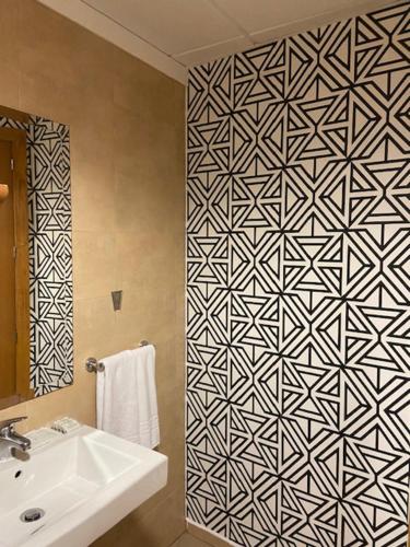 a bathroom with a black and white patterned wall at Apartamentos Avenida in Seville