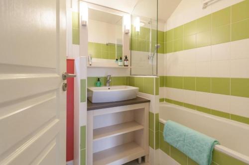 een badkamer met een wastafel, een bad en een spiegel bij l'appartement la Pommeraie in Branville