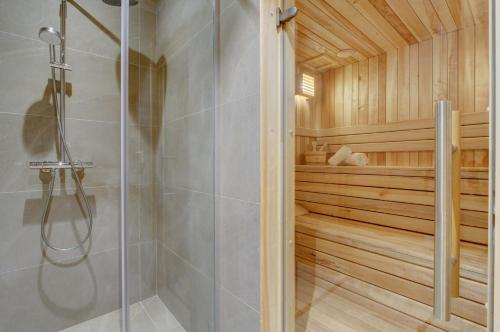 - un sauna avec une douche et une porte en verre dans l'établissement Chalet La Mésange Azurée, à Morzine