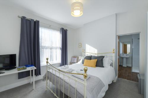 a bedroom with a white bed and a television at Borrowfield Lodge in Derby
