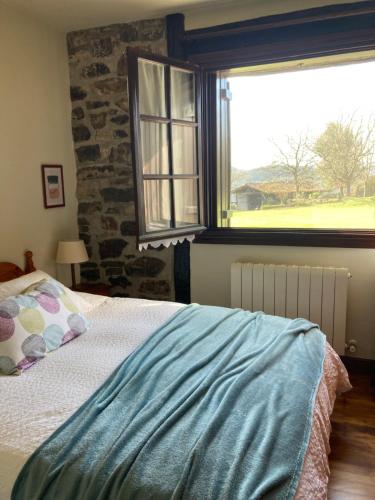 a bedroom with a bed and a large window at Lekunberri Baserria in Arrieta