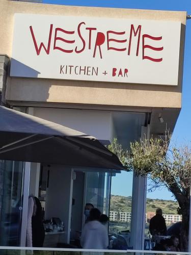 a sign for a restaurant with people sitting at tables at BEACHFRONT with Seaviews Apartment No56 Award Winner Unbeatable Location for Closeness to the Sea Ideal for Guests looking for Winter Spring and Autumn Breaks in Sunny Malta Also Ideal for Coastal Hikers in Mellieħa