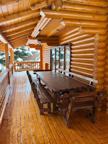 a wooden deck with a wooden table and benches at Provintsia in Migovo