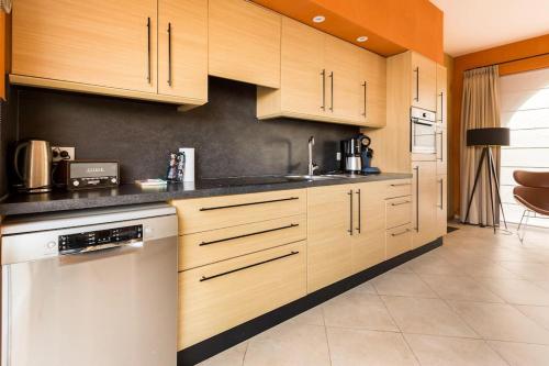a kitchen with wooden cabinets and a white dishwasher at De Notelaar in Alveringem