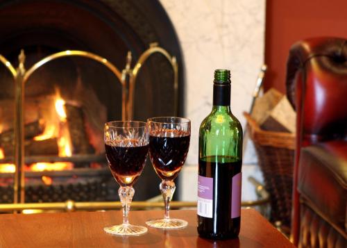 a bottle of wine sitting on a table with two glasses at Shap Wells Hotel in Shap