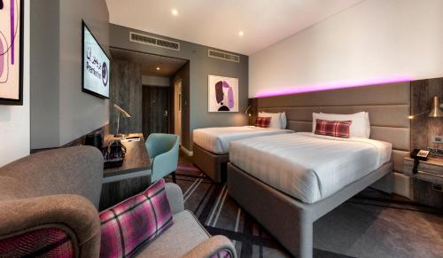 a hotel room with two beds and a couch at Premier Inn Dubai Barsha Heights in Dubai