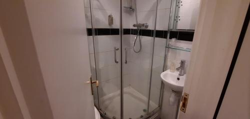 a bathroom with a glass shower and a sink at Colebrook Guest House in Farnborough