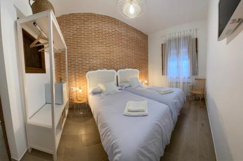 a large bed in a room with a brick wall at Casa Elsa Almagro in Almagro