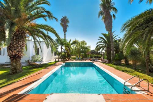 einen Pool mit Palmen vor einem Haus in der Unterkunft Villa with swimming pool Salento - Villa Le Due Sorelle in Ugento