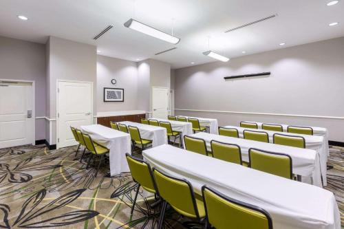 an empty room with white tables and yellow chairs at La Quinta by Wyndham Houston NW Beltway8/WestRD in Houston