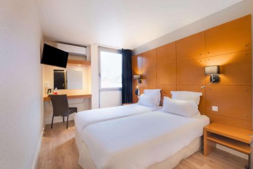 a hotel room with a large white bed and a desk at Comfort Hotel Lille L'Union in Tourcoing