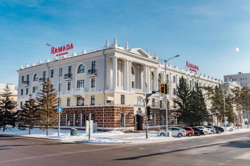 a large white building on the corner of a street at Ramada by Wyndham Astana in Astana