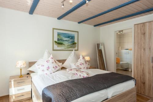 a bedroom with a large bed with pink pillows at Hotel garni NordSeerose Greetsiel in Krummhörn