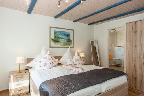 ein Schlafzimmer mit einem großen Bett mit rosa Kissen in der Unterkunft Hotel garni NordSeerose Greetsiel in Krummhörn