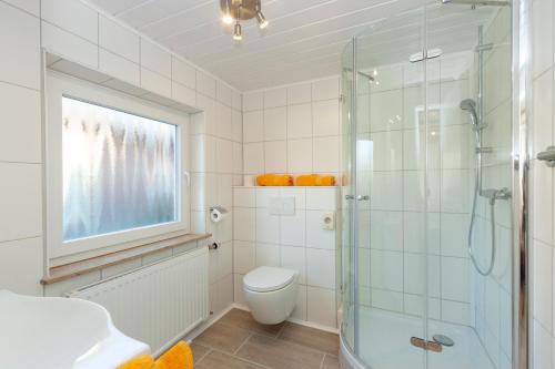 ein Badezimmer mit Toilette und Glasdusche in der Unterkunft Hotel garni NordSeerose Greetsiel in Krummhörn
