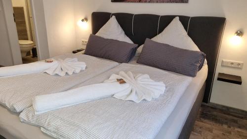 ein Bett mit zwei weißen Handtüchern darüber in der Unterkunft Pension Likedeeler Doppelzimmer John Rackham in Borkum