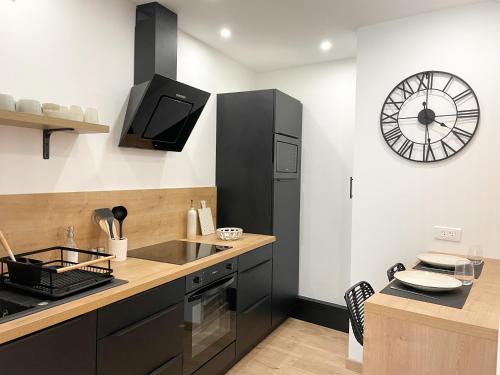 eine Küche mit Spüle und einer Uhr an der Wand in der Unterkunft COZYMAINE, superbe studio au coeur d'Angers in Angers