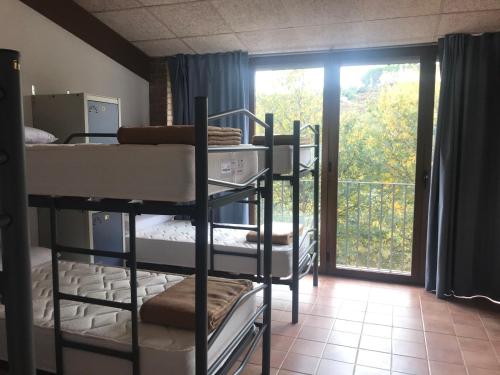 a room with three bunk beds and a balcony at Albergue de Castillazuelo in Castillazuelo