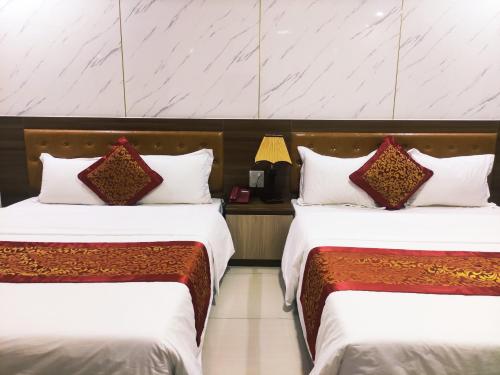 two beds in a hotel room with white and red pillows at Victory Hotel, số 7, Vương Thúc Mậu, Tp Vinh in Vinh