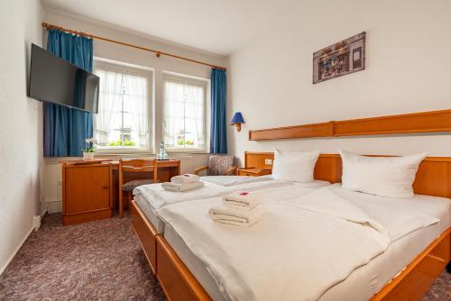 a bedroom with a large bed with towels on it at Hotel & Restaurant Stadt Genthin in Genthin